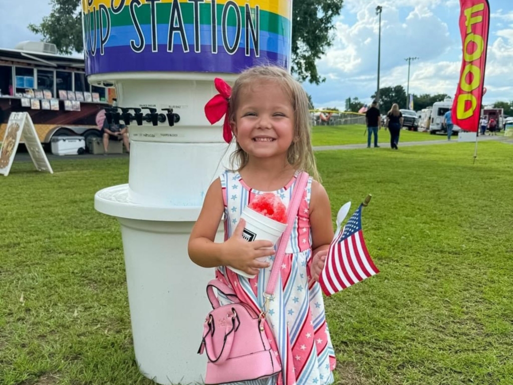 Girl enjoys snow-cone with American flag in hand